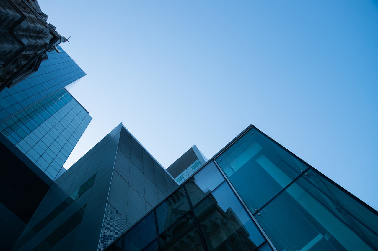 Low angle view of modern skyscrapers with glass facades against a clear blue sky.
